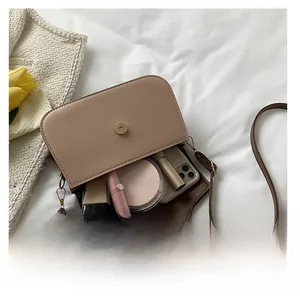Interior storage space of beige leather crossbody bag showing phone and cosmetics