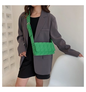 Fashionable bright green quilted crossbody bag shown on a model in a stylish grey suit