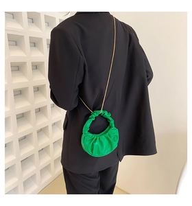 Detail of bright green pleated cloud bag featuring a gold chain and soft PU texture