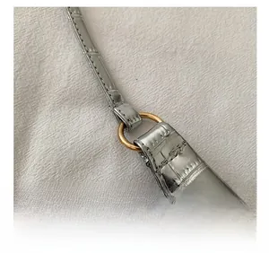 Close-up of silver stone pattern tote bag showing gold metal hardware and strap detail