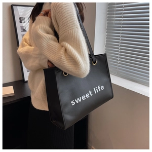 Dettaglio borsa shopper nera con testo sweet life e anelli metallici dorati