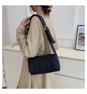 Detail view of black quilted nylon shoulder bag with adjustable silver eyelet strap
