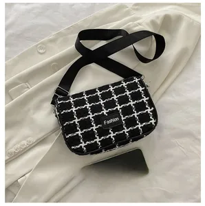 Dettaglio della borsa a quadri in tweed con etichetta Fashion accanto a un cellulare