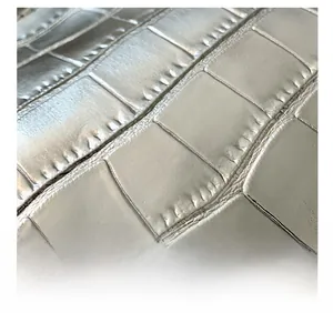 Macro shot of silver crocodile embossed texture on luxury handbag with deep metallic finish