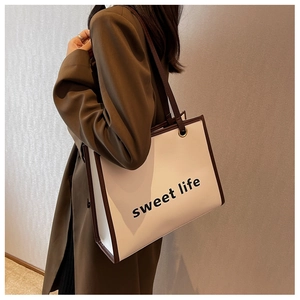 Dettaglio di borsa tote beige con finiture in pelle marrone e stampa sweet life