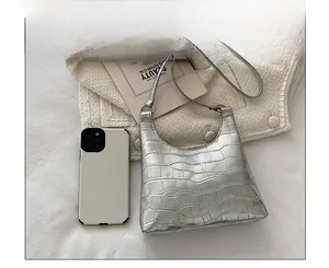 Silver crocodile embossed moon bag shown next to a smartphone for size reference