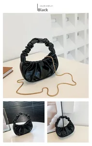 Macro shot of black pleated cloud bag texture with golden chain and gathered handle