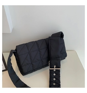 Macro detail of black quilted shoulder bag featuring silver buckle and metal eyelets