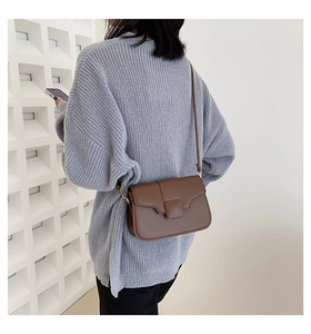 Detail of dark brown matte leather crossbody bag paired with a gray knit sweater