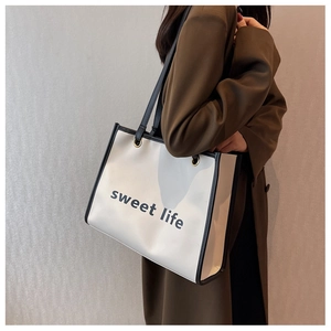 Dettaglio della borsa shopper crema con finiture nere e stampa scritta sweet life