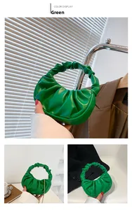 Detail of green pleated half-moon handbag with cloud-like texture and soft handle