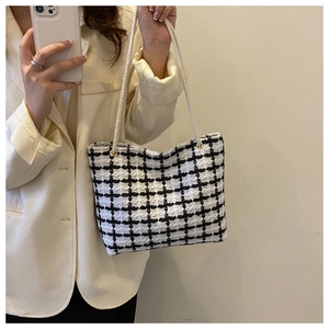 Detail of checkered tweed tote bag with braided rope handles on a blazer-clad model