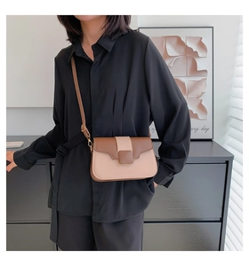 Detail shot of the two-tone beige and brown crossbody bag with square buckle on model