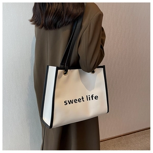 Vista laterale della borsa tote in pelle bianca con scritta indossata dal modello