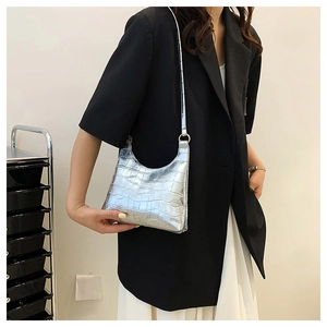 Close-up of silver crocodile pattern shoulder bag with golden ring hardware and curved design