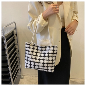 Detail of checkered woven tote bag with white rope handles and golden metal eyelets