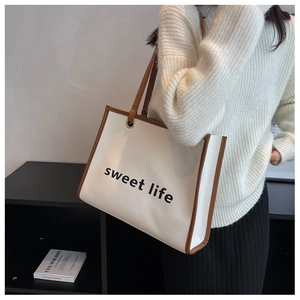 Borsa tote crema con manici marroni e stampa 'sweet life' indossata da una modella