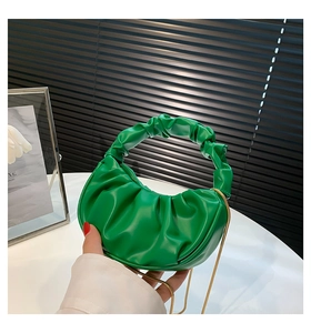 Close-up of emerald green ruched handbag with elegant gold chain strap detail
