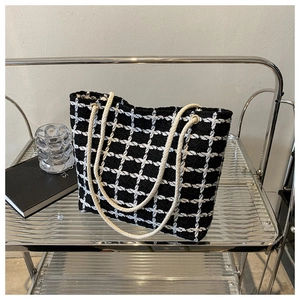Close-up of black and white checkered tote bag with woven texture and cotton rope handles