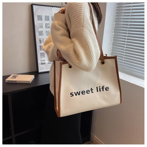 Dettaglio della grande borsa tote crema con manici marroni e scritte sweet life nere