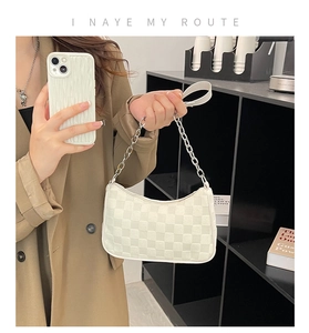 Detailed view of white checkered shoulder bag featuring metallic chain and leather handle