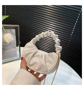Detail of white pleated cloud bag featuring golden chain strap and soft leather texture