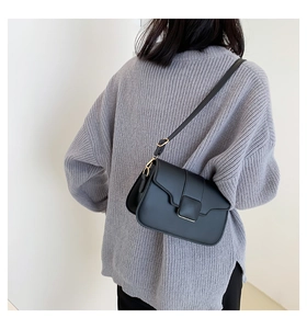Classic black square shoulder bag with gold buckle detail shown on a model