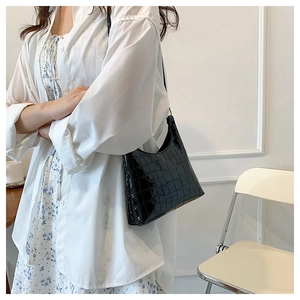 Detail of the glossy black crocodile-embossed leather texture on the hobo shoulder bag