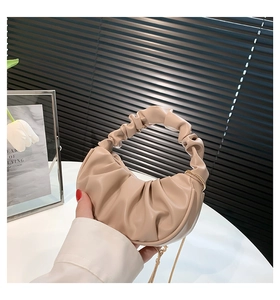 Close-up of ruched beige cloud bag with elegant gold chain and pleated handle detail