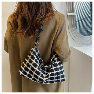 Detailed view of black and white plaid hobo bag with knotted leather shoulder strap