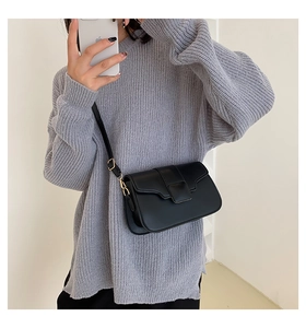 Detail of black leather square crossbody bag with gold metal buckle and adjustable strap