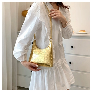 Close-up of golden crocodile pattern shoulder bag with polished metallic finish for women
