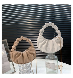 Detail of pleated cloud bags in beige and ivory with golden chain and soft PU texture