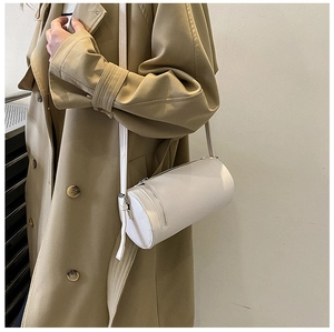 Minimalist beige barrel crossbody bag with smooth leather texture and slim shoulder strap
