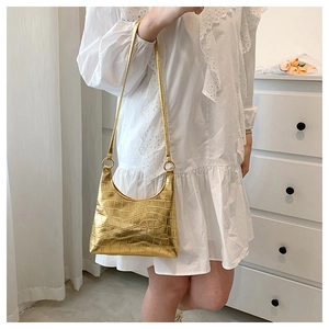 Detail of gold faux crocodile pattern tote bag featuring metallic finish and chain rings