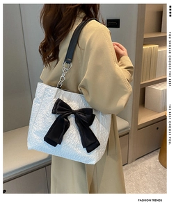 Détail du sac cabas plissé blanc avec grand nœud en satin noir et bandoulière chaîne