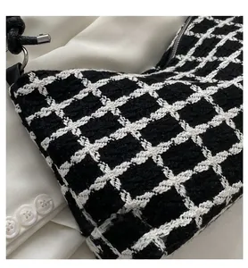 Close-up of black and white plaid tweed fabric with silver zipper and leather strap