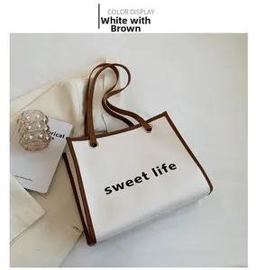 Dettaglio della borsa shopper bianca e marrone con scritta sweet life e texture in PU