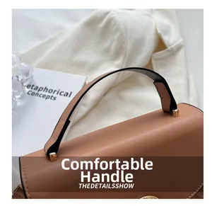 Detail of comfortable light brown leather handle with gold hardware on a chic crossbody bag
