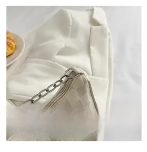 Detail of silver chain strap on cream white checkered fabric underarm bag