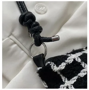 Macro shot of black and white tweed bag with silver metal ring and twisted strap detail