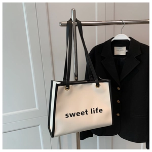 Dettaglio della borsa tote crema con scritta sweet life e bordi neri a contrasto