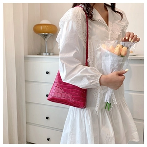 Close-up of bright rose pink crocodile pattern texture on a stylish underarm bag
