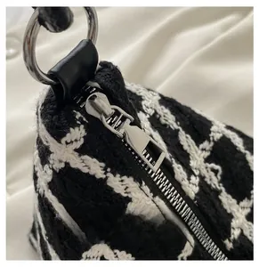 Detail of silver smooth zipper and black-and-white checkered woven fabric on tote bag