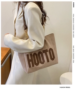 Detail of light brown tote bag featuring HOOTO embroidered lettering and chain shoulder strap