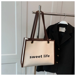 Dettaglio della borsa bianca con scritta sweet life, manici marroni e finiture dorate
