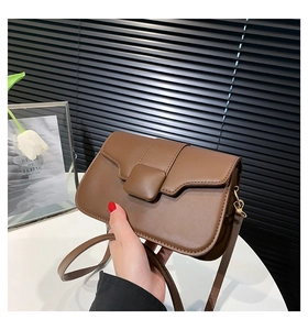 Detailed close-up of a dark brown leather crossbody bag with a square decorative buckle