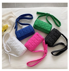 Flat lay of colorful quilted crossbody bags in white, blue, green, pink, and black