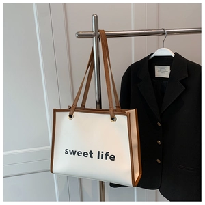 Dettaglio della borsa shopper bianca con scritta nera sweet life e rifiniture in marrone