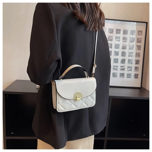Detail of cream quilted crossbody bag with golden clasp and textured leather finish